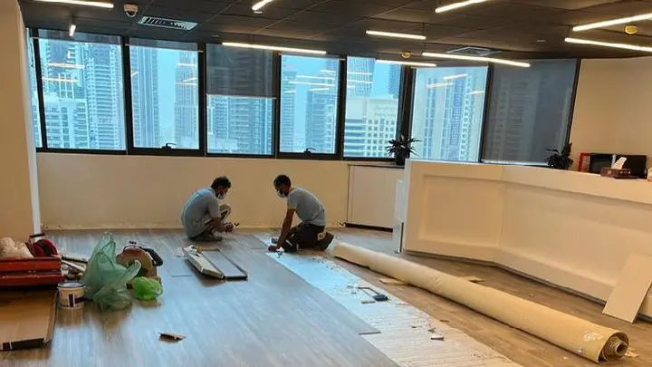 pemasangan-flooring-kantor-area-kerja Proses pemasangan flooring kantor area kerja oleh teknisi profesional menggunakan lantai kayu vinyl minimalis.