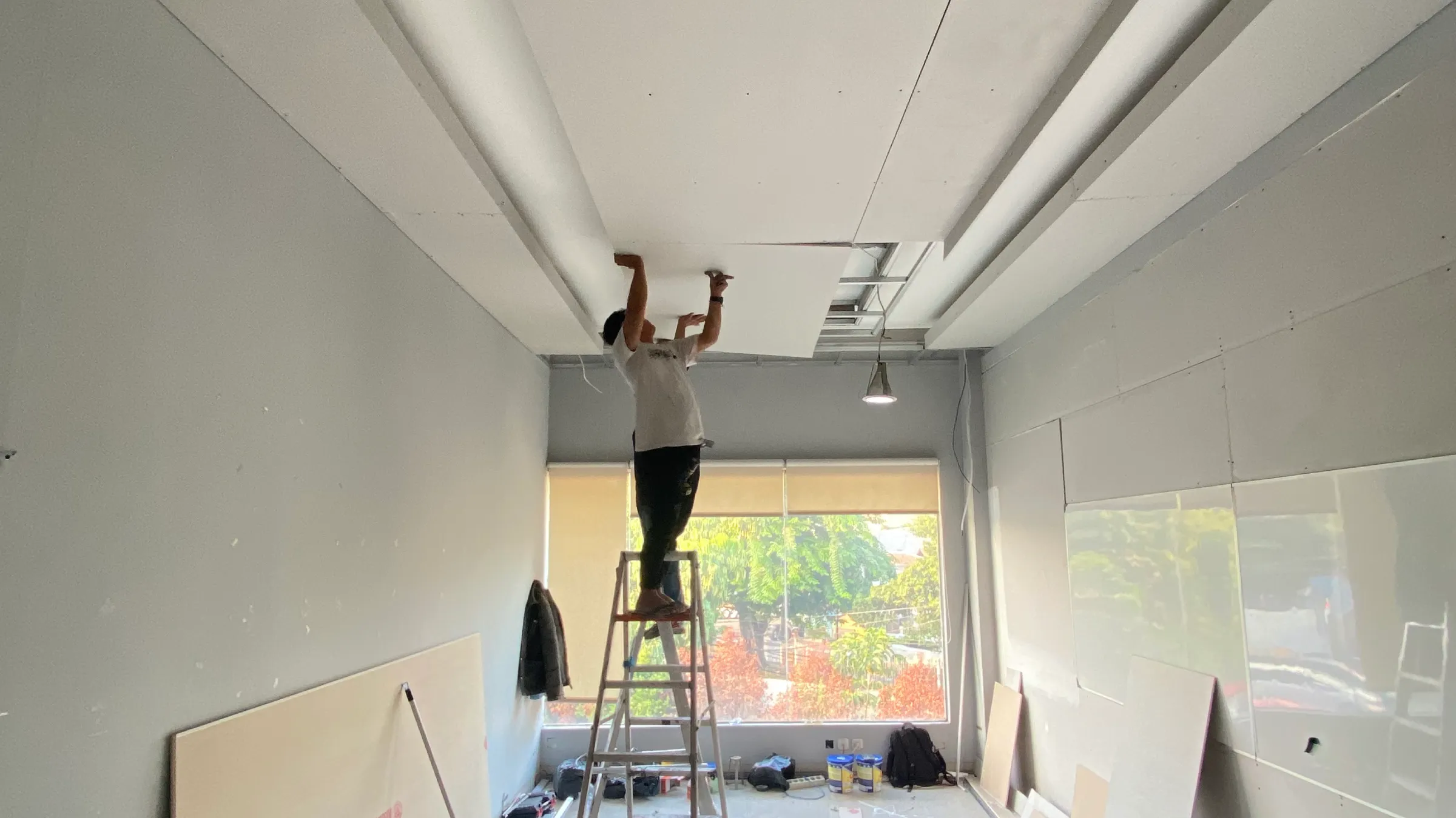 proses pengerjaan kontraktor interior plafon office Tim teknis dari kontraktor interior sedang melakukan pemasangan drop ceiling gypsum pada proyek renovasi kantor di Jakarta.