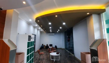Hasil peremajaan ruang tunggu lounge kantor modern dengan aplikasi plafon drop ceiling gypsum lengkung bertingkat dan lampu hidden LED